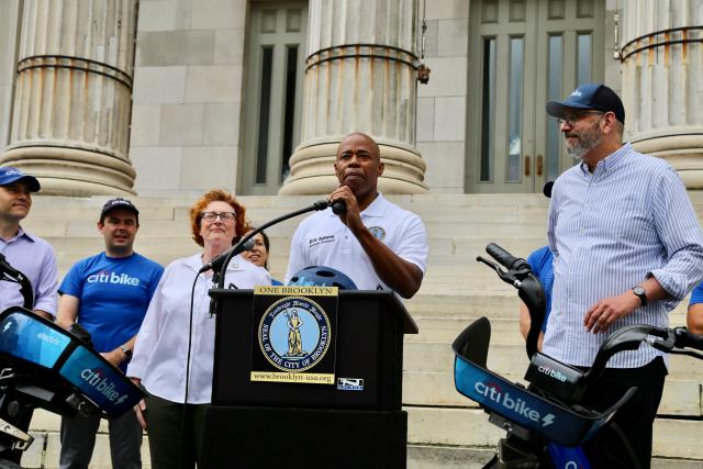 Brooklyn Borough President Adams in front of Brooklyn Borough Hall, surrounded by Pedal Assist Citi Bikes.