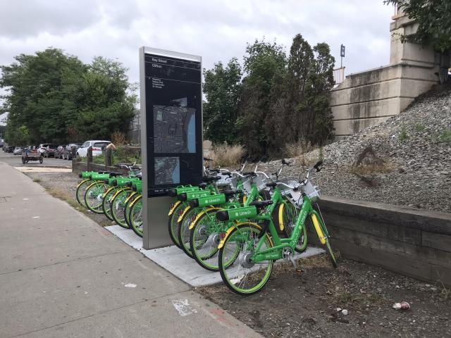 A row of Lime bikes neatly lined up near a Staten Island Railroad station. 