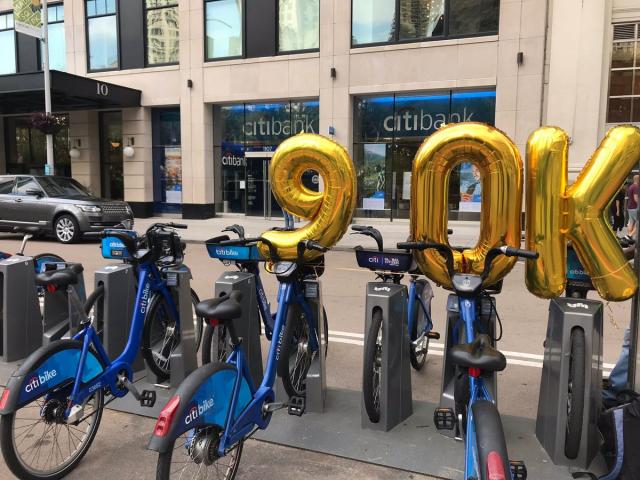 Gold balloons reading "90 K" over a Citi Bike station. 