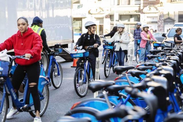 A photo of a group of people checking out multiple Citi Bikes. 