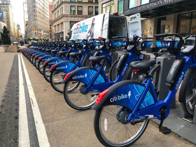 A row of Citi Bikes, all with a lightning bold on the back fender. This shows it is an electric bike.