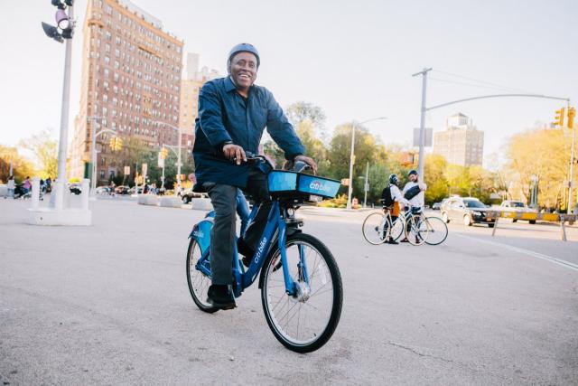 A person happily riding a Citi Bike near Grand Army Plaza
