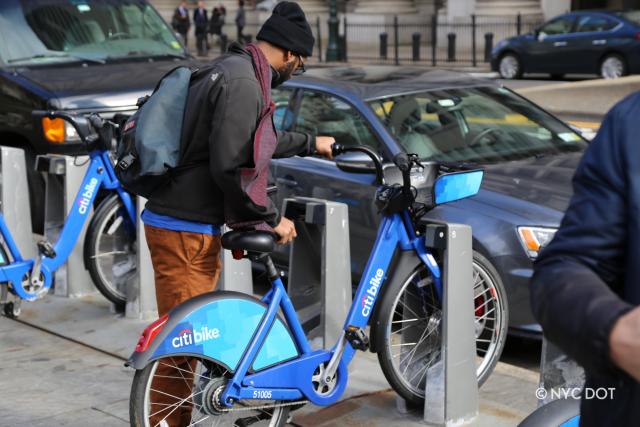 A person adding checking out a Citi Bike at a station. 