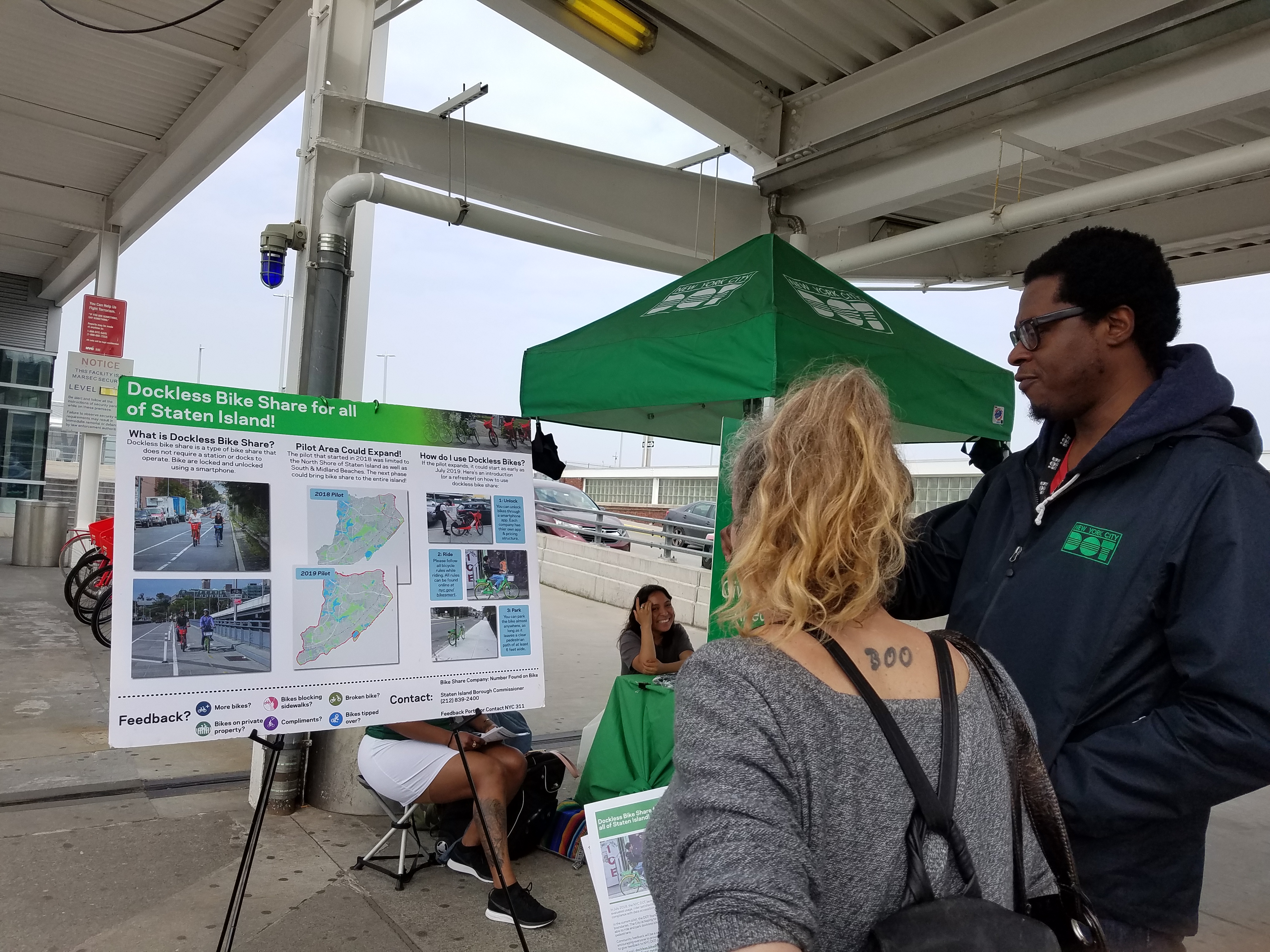 An Ambassador pointing to a poster board, detailing the possible dockless project. 
